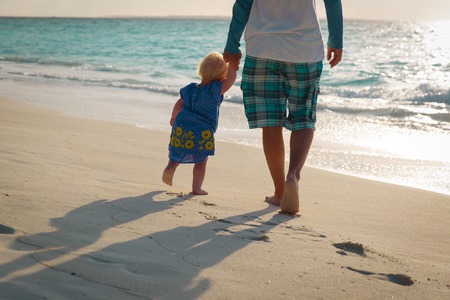 Silhouette of father and little daughter walk at sunset