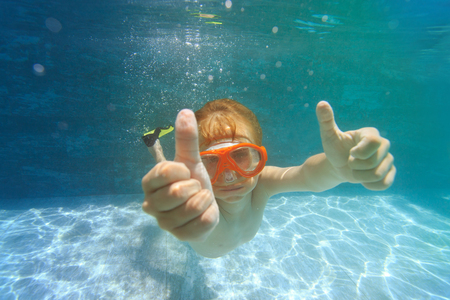 happy little boy swim underwater with thumbs upの写真素材