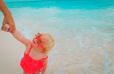 cute little baby girl on beach holding mother hand, family at beachの写真素材