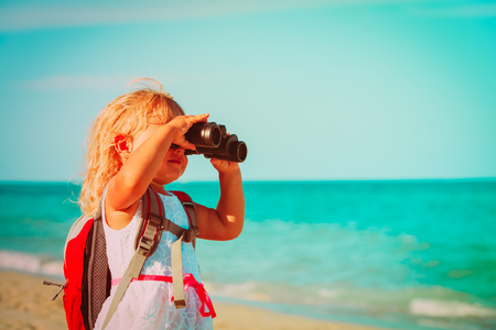little girl travel on beach, looking through binocularの写真素材