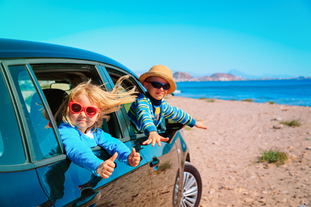 little boy and girl enjoy travel by car at beachの写真素材