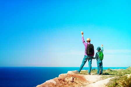 happy family travel - father and son hiking in mountains at seaの写真素材