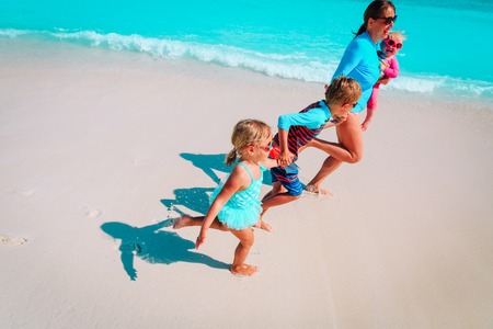 mother with kids play with water run on beachの写真素材