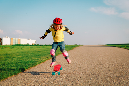 little girl learn to ride on skateboard outsideの写真素材