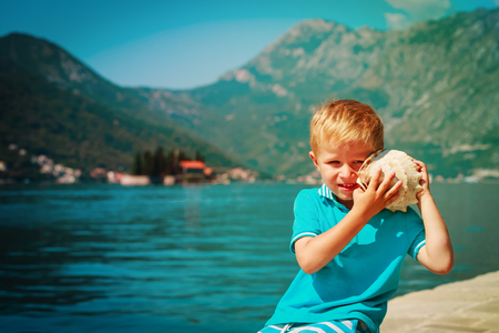 little boy listening to shell in Kotor bay, Montenegro, vacation and travelの写真素材