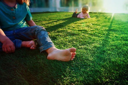 summer in the city- kids play bare foot on grass in urban backgroundの写真素材