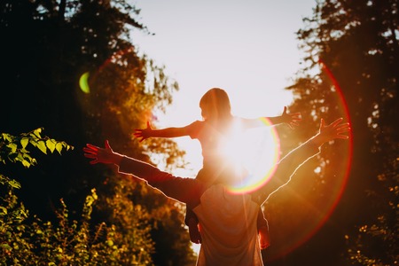 Father and little daughter silhouettes play at sunset natureの写真素材