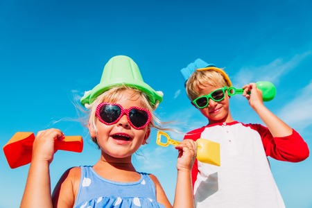 cute little boy and girl play with toys on beach