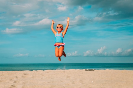 happy little girl play jump at beachの写真素材