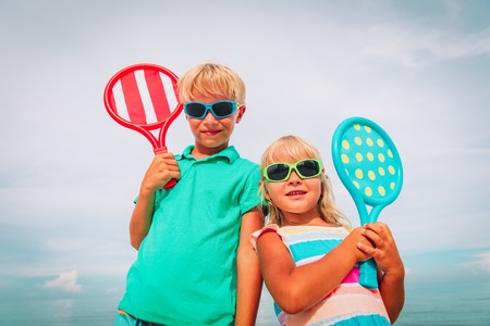 kids- boy and girl- play tennis on beachの写真素材