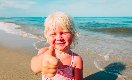 happy little girl thumb up enjoy tropical beachの写真素材