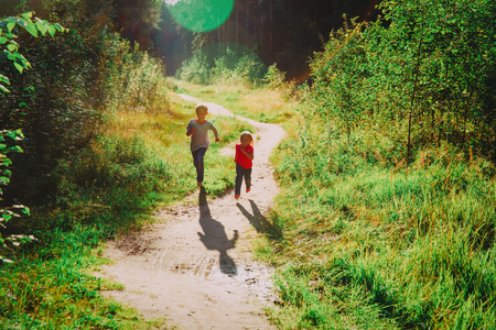 happy little boy and girl running at sunset natureの写真素材
