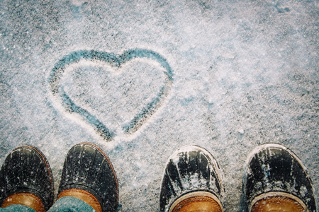 love winter - feet in snow boots and heart in natureの写真素材