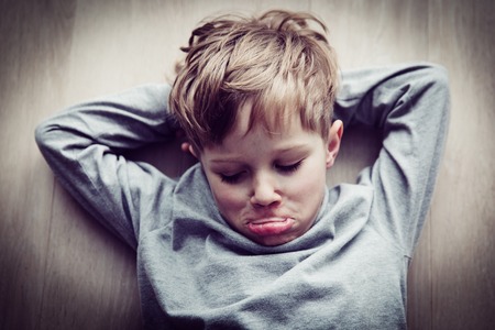 little boy feels annoyed grumpy lying on the floor
