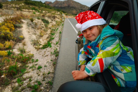 christmas car travel- happy little girl loves travel in winterの写真素材