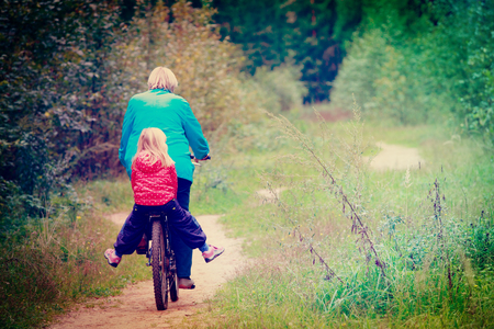 active senior grandmother with granddaughter on bike in natureの写真素材