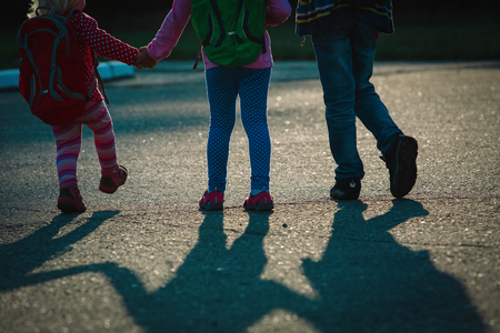 kids with backpacks coming for shool at sunsetの写真素材
