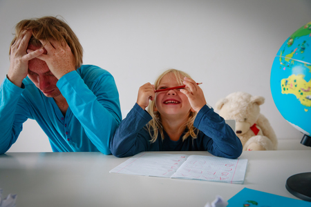 father is tired and exhaused making homework with little daughter play smileの写真素材