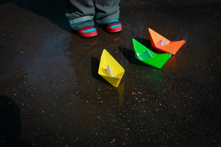 child playing with paper boats in water puddleの写真素材