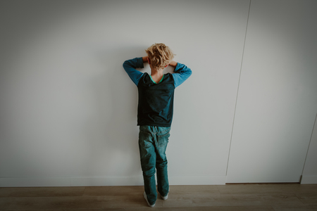 young boy standing up against a wallの写真素材