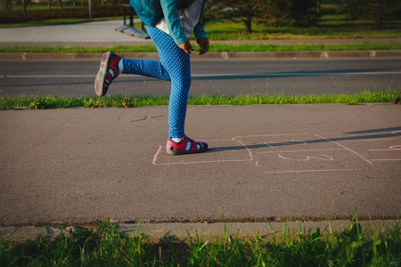 little girl play hopscotch on playground outdoorsの写真素材