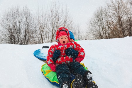 little boy and girl slide in winter snowの写真素材