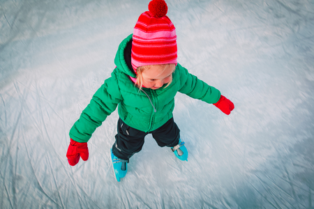 happy little girl learning to skate in winterの写真素材