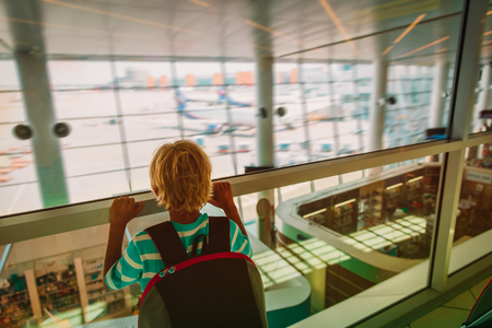 little boy with backpack looking at planes in airportの写真素材