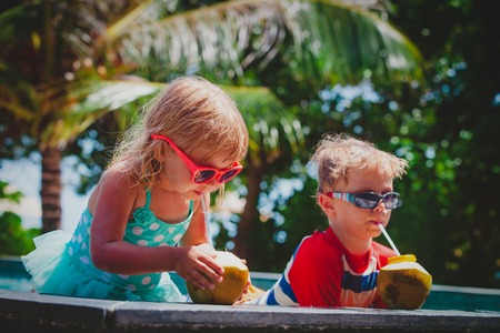happy kids drinking coconut cocktail on beach resortの写真素材