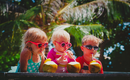 happy kids drinking coconut cocktail on beach resortの写真素材