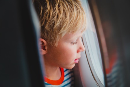 little boy travel by plane looking through windowの写真素材
