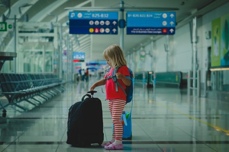 little girl with suitcases travel in airport, family vacationの写真素材