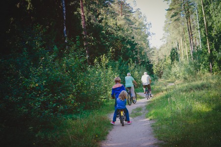 senior grandparents with kids riding bikes in natureの写真素材