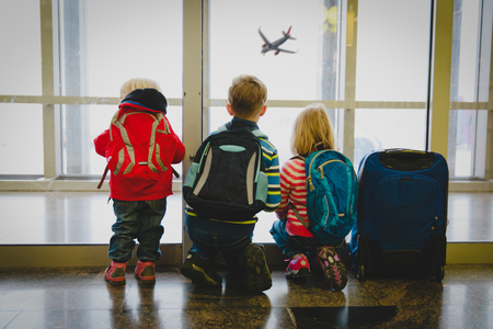 kids waiting for travel looking at planes in airportの写真素材