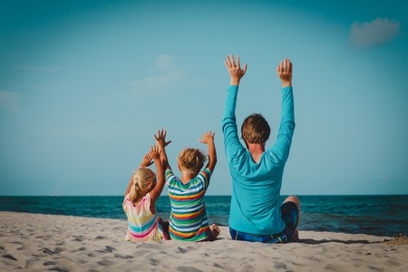 father with little son and daughter having fun on beachの写真素材