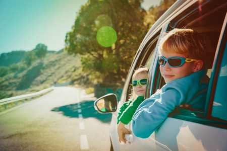happy little boy and girl enjoy travel by car in mountainsの写真素材