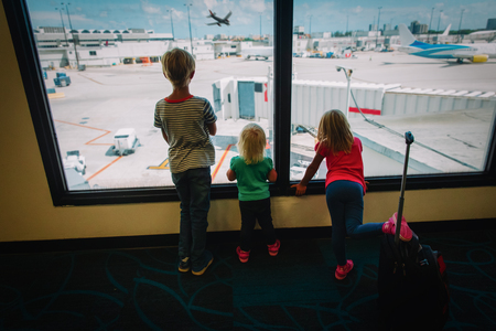 kids waiting for travel looking at planes in airportの写真素材