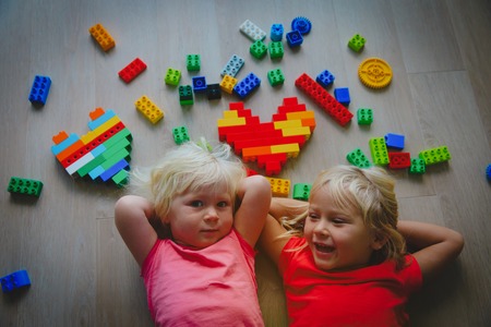 happy cute girls enjoy playing with plastic blocksの写真素材
