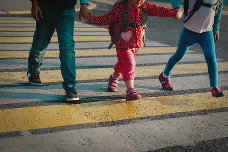 boy and girls holding hands go to school crossing the roadの写真素材