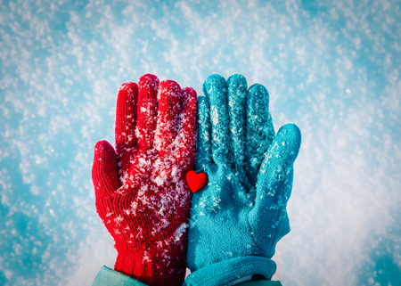 Hands in gloves holding heart in winter natureの写真素材