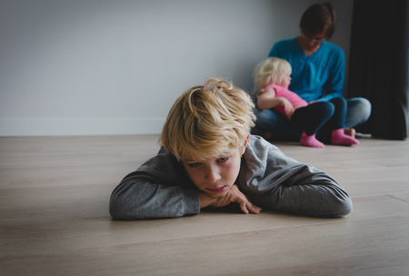 siblings rivalry- sad son and dad holding baby daughterの写真素材