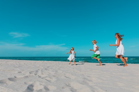 mother with kids play run on tropical beachの写真素材