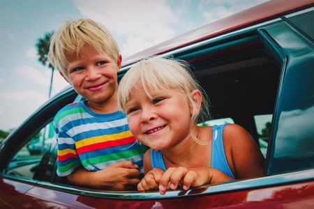 happy little boy and girl travel by car on summer vacationの写真素材
