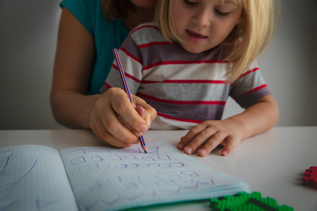 mother teaching daughter how to write lettersの写真素材