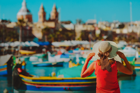 young woman looking at traditional boats in quay of Malta, travel conceptの写真素材