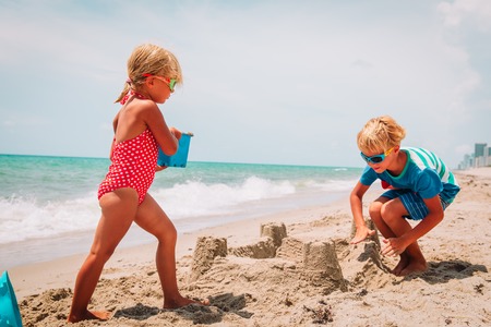 kids-boy and girl- play with sand on tropical beachの写真素材