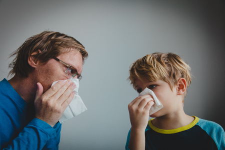 father and son wiping and blowing nose, infection or allergyの写真素材