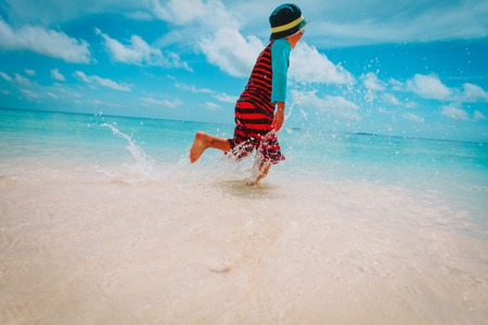 little boy run splashing water on beach