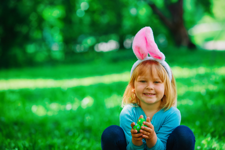 happy cute little girl on easter eggs hunt in springの写真素材