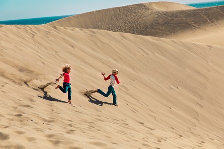 happy boy and girl play in sand dunesの写真素材